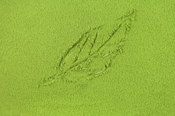 Green matcha tea powder background with tea leaf pattern, top view.