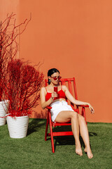 A girl on an orange background with a red tin can in her hands. Cheerful girl, advertising shooting