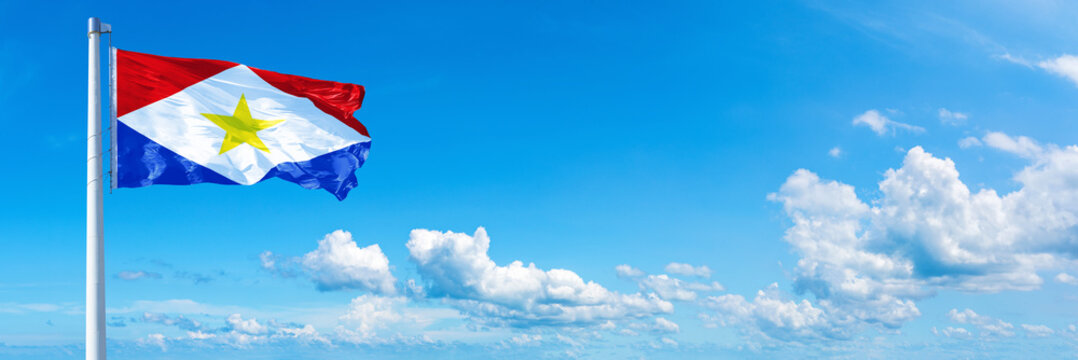 Saba flag waving on a blue sky in beautiful clouds - Horizontal banner