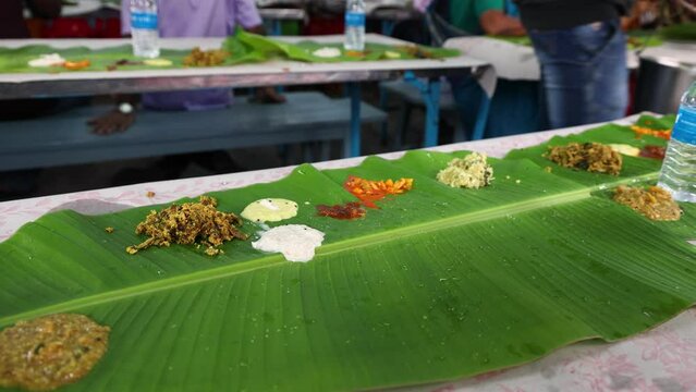 People eating traditional Indian wedding marriage sadhya rice Sambar, parippu dal curry ghee Payasam on banana leaf Onam Vishu Pongal Diwali festival vegetarian food Kerala Tamil Nadu South India.