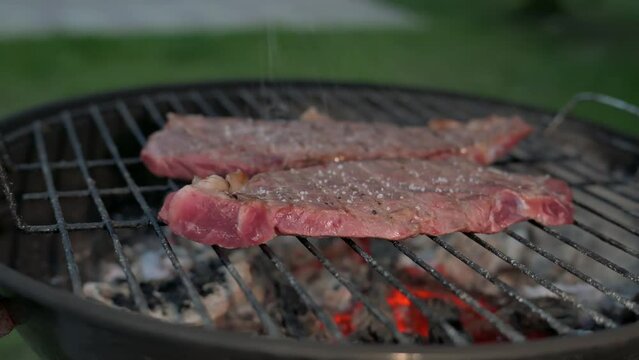 Man cooking and rotating beaf steakes on grill. 4k video footage