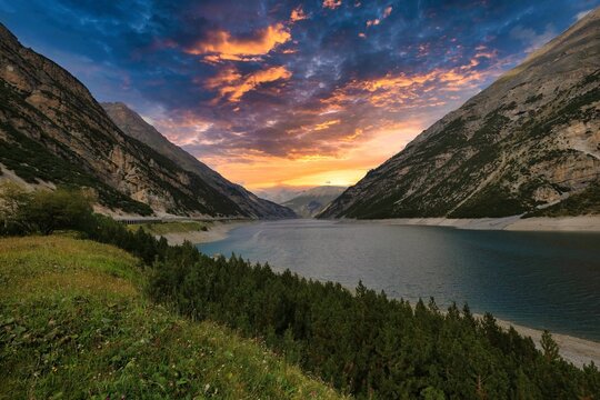 Beautiful lake surrounded by big rocky mountains under a beautiful sunset sky in Livigno