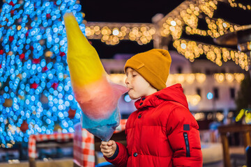 Boy with cotton candy at christmas market. Happy child on Christmas market. Traditional leisure for...