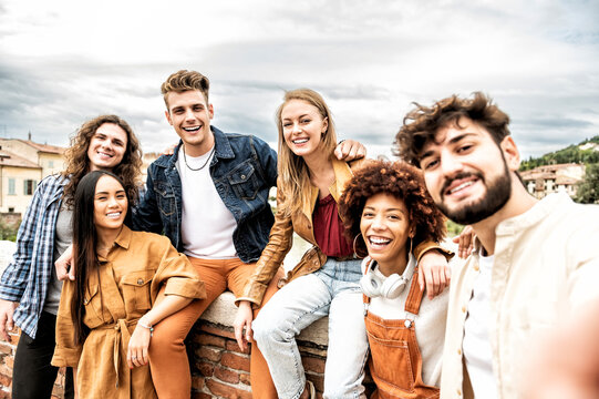 United group of happy young friends having fun while taking a selfie with mobile phone outdoors - Multiracial students people looking at the camera smiling - Friendship and holidays concept