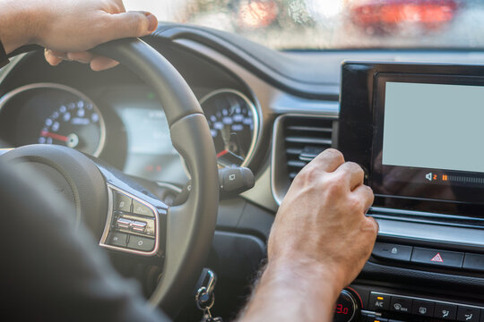 
male hands on the car steering wheel and touching the buttons on the multimedia screen