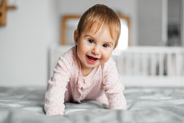 Fototapeta premium Girl baby in pink pajamas on bed.