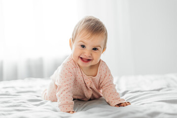  Girl baby  in pink pajamas on bed.