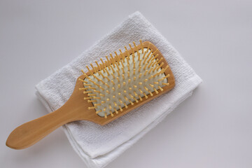 Wooden comb on white towel background. Modern paddle hair brush on table. Top view, flat lay, copy space.  - obrazy, fototapety, plakaty