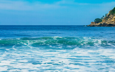 Beautiful surfer waves rocks cliffs at beach Puerto Escondido Mexico.