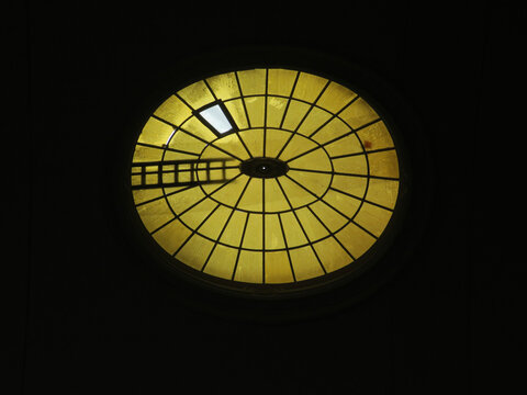 ladder on an oval formed window on top of the roof of a church