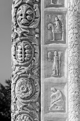 Black and white photo showing in detail decorative elements carved in marble pillar and wall of church in Pisa