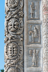 Close-up on decorative elements carved in marble pillar and wall of church in Pisa