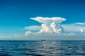 beautiful seascape with a huge mushroom cloud on the horizon, silhouette of a tanker on the horizon