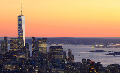 Aerial view of Lower Manhattan skyline illuminated at sunset with orange background in New York...