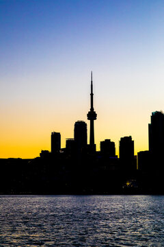 CN Tower and Toronto skyline with lake reflection during sunset or golden hour, city light after sunset
