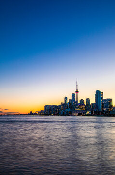 CN Tower and Toronto skyline with lake reflection during sunset or golden hour, city light after sunset