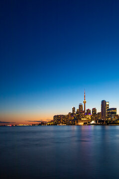 CN Tower and Toronto skyline with lake reflection during sunset or golden hour, city light after sunset