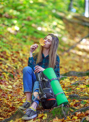 Fototapeta na wymiar Pensive girl in casual style with backpack walks, travels and hikes in beautiful sunny forest park alone