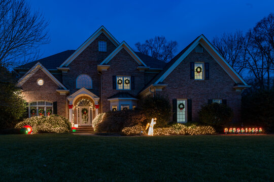 Holiday light decorations at night in front of a large brick house