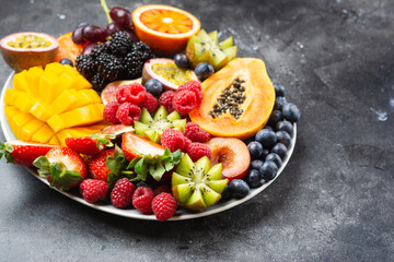 Delicious fruit platter mango pomegranate raspberries papaya oranges passion fruits berries on oval...