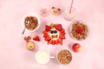 Healthy breakfast with ingredients, fun food for kids. The concept of healthy and natural food. Oatmeal or cottage cheese with muesli, banana and strawberries, nuts and cookies, top view,