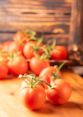 Defocused tomatoes, beautiful details of fresh red tomatoes on vines on rustic wood, blurred.