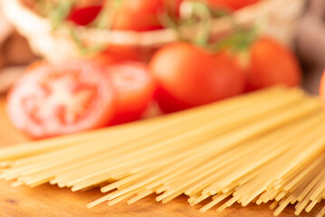 Pasta, beautiful details of red tomatoes and strands of raw spaghetti over rustic wood, selective...
