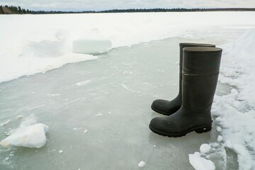 Closeup shot of black rain boots on a frozen land during the snow season