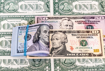 Folded american dollars banknotes wrapped by rubber band over dollars banknotes
