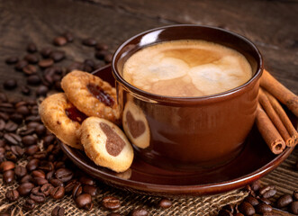 coffee with milk in a ceramic brown cup with cookies on a saucer
