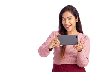 Cheerful young woman watching video in mobile phone isolated on white.