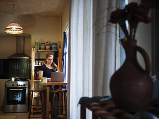 Young woman working on laptop while drinks morning coffee home