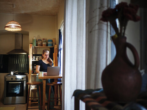 Young woman working on laptop while drinks morning coffee home - Powered by Adobe