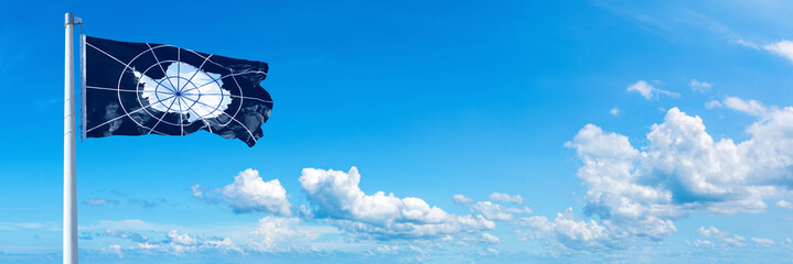 Antarctic Treaty System flag waving on a blue sky in beautiful clouds - Horizontal banner