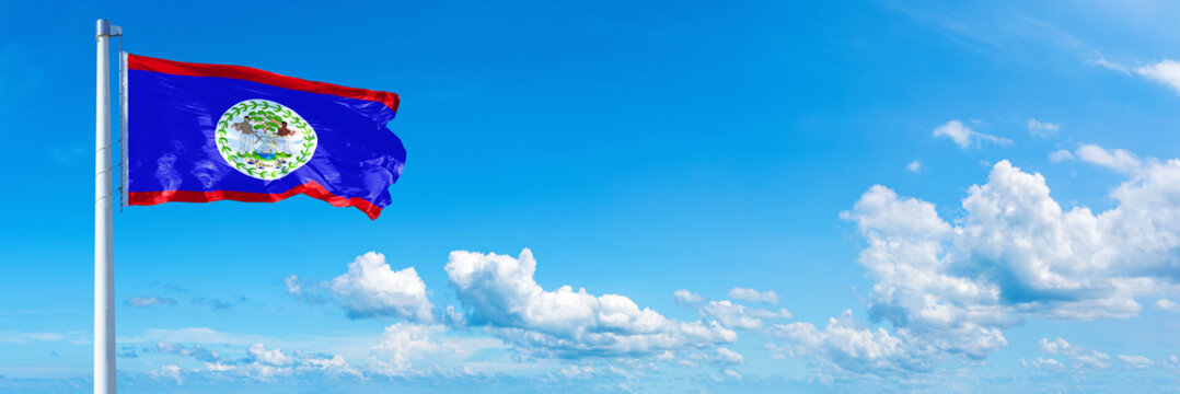 Belize flag waving on a blue sky in beautiful clouds - Horizontal banner