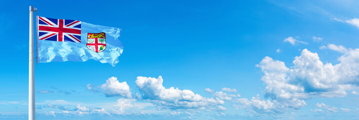 Fiji flag waving on a blue sky in beautiful clouds - Horizontal banner