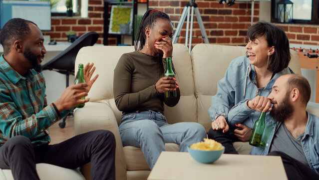 Happy People Laughing And Telling Funny Story At Party Gathering, Drinking Beer From Bottles And Enjoying Hangout. Friends Talking About Memories At Casual Social Event, Leisure Weekend Activity.