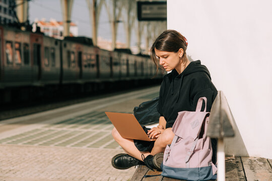 Female student working on laptop on the train station