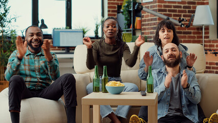 Obraz premium Diverse people watching football game on television and cheering to win championship with favorite soccer team. Sport fans enjoying tournament match, showing support in championship. Tripod shot.