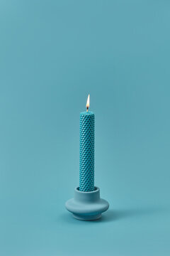 Burning beeswax candle with cell pattern.