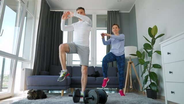 Caucasian couple doing cardio training at home in cozy bright room