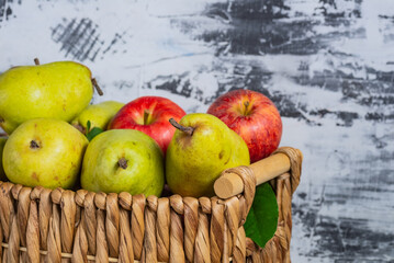 pears and apples in a wicker basket. New crop with fresh fruits.