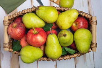 pears and apples in a wicker basket. New crop with fresh fruits.