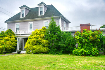 small two-story American house with a well-groomed lawn in a seaside village.