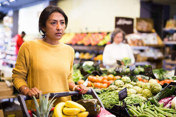 Obraz premium Casual woman doing shopping in grocery department of supermarket