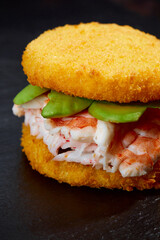 Pan-Asian cuisine concept. Japanese sushi burger made from rice bread, crab meat, avokado and wasabi sauce. Serving on wooden board. copy space