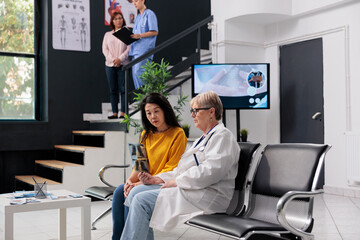 Naklejka premium Senior doctor and asian patient looking at x ray scan results, explaining illness diagnosis with radiography at health center. Physician giving support with prescription treatment, healthcare advice.