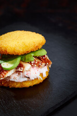 Pan-Asian cuisine concept. Japanese sushi burger made from rice bread, crab meat, avokado and wasabi sauce. Serving on wooden board. copy space