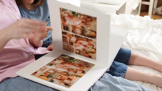 mother and daughter flip through a photobook with photos of a family photo shoot
