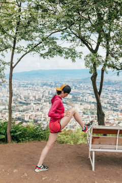 The girl is doing fitness at a height with a view of the city